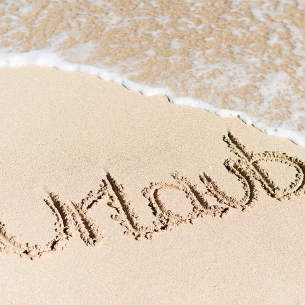 Foto Strand mit Welle und Schriftzug Urlaub
